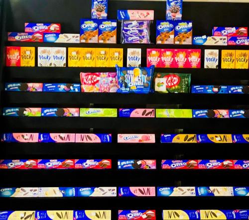 A colorful display of various snack boxes, including Pocky, Oreos, and Kit Kats, arranged in neat rows.