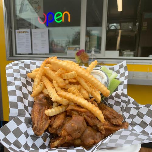 A plate of crispy chicken wings and crinkle-cut fries served in a checkered paper container.