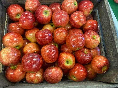 A wooden crate filled with shiny red apples stacked closely together.