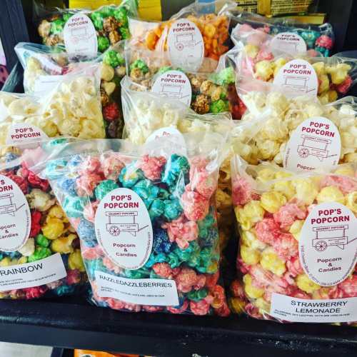Colorful bags of popcorn in various flavors, including rainbow, razzleberry, and strawberry lemonade, displayed on a shelf.