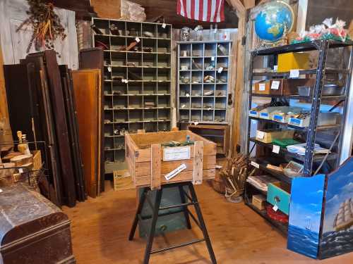 A rustic shop interior with wooden shelves, a globe, and various vintage items displayed around a central wooden crate.