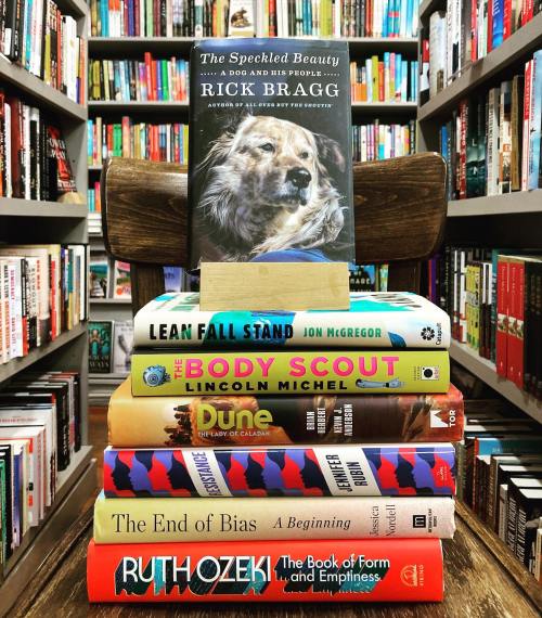 A stack of books with "The Speckled Beauty" by Rick Bragg on top, surrounded by colorful book spines in a bookstore.