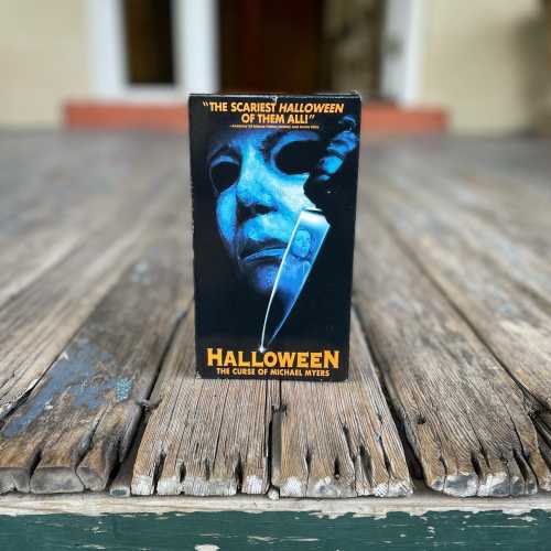 A VHS cover for "Halloween: The Curse of Michael Myers" featuring a blue-toned mask and a knife on a wooden surface.