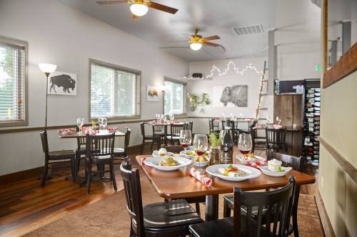 A cozy restaurant interior with wooden tables, chairs, and decorative lighting, featuring plates of food and wine glasses.