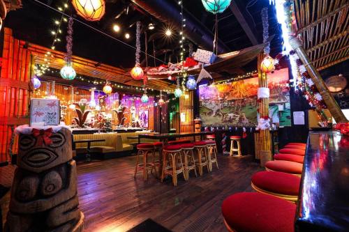 A vibrant tiki-themed restaurant with bamboo decor, colorful lanterns, and festive holiday decorations.