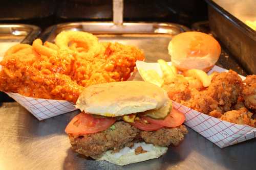 A variety of fried foods including a chicken sandwich, onion rings, and fried chicken in paper trays.