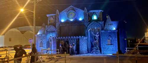 A spooky castle facade illuminated at night, with figures and eerie lighting, set up for a Halloween event.