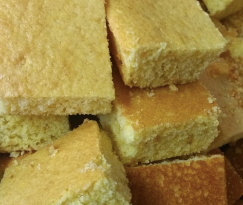 A close-up of freshly baked, golden-brown squares of cornbread stacked together.
