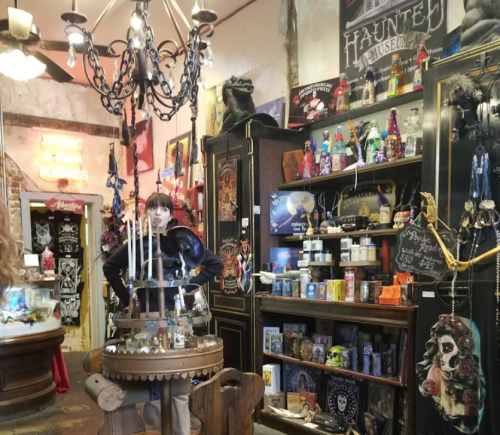 A cozy shop interior filled with eclectic decor, candles, and colorful items, featuring a person standing by a display.