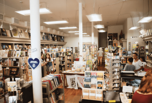 A cozy bookstore filled with shelves of books, customers browsing, and a warm, inviting atmosphere.