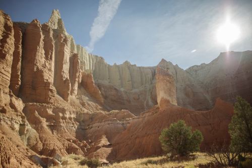 A stunning canyon landscape with towering rock formations and a bright sun shining in a clear blue sky.