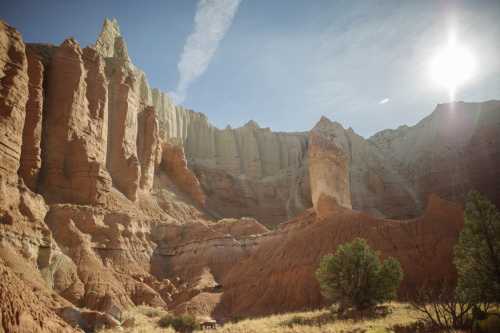 A stunning canyon landscape with towering rock formations and a bright sun shining in a clear blue sky.