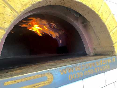 A wood-fired oven with flames visible inside, showcasing a warm, inviting cooking environment.