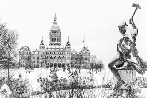 A snowy scene featuring a statue of a warrior in front of a grand, domed building.