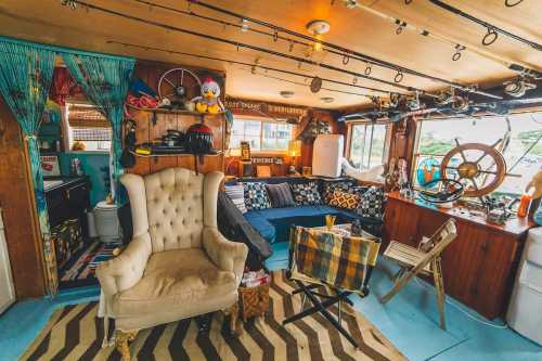 Cozy interior of a boat with a vintage armchair, nautical decor, and a mix of furniture and fishing gear.