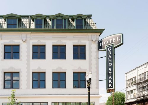 Exterior of the Grand Stark Hotel, featuring a green roof and a large illuminated sign that says "OPEN."