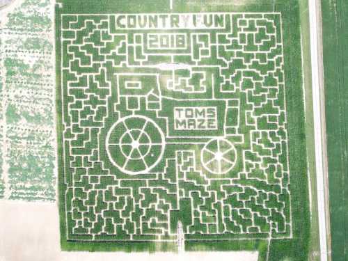 Aerial view of a corn maze shaped like a tractor, featuring the words "Country Fun 2019" and "Tom's Maze."