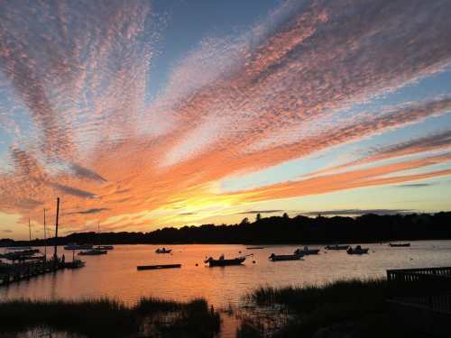 A vibrant sunset over a calm waterway, with boats and colorful clouds reflecting in the sky.
