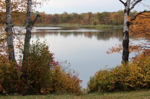 A serene lake surrounded by autumn foliage, with colorful trees reflecting on the calm water.
