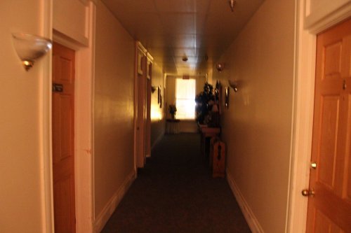 A dimly lit hallway with doors on either side and a light source at the end, creating a warm atmosphere.