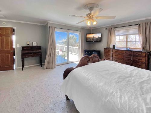 Spacious bedroom with a wooden bed, dresser, TV, and large windows overlooking a patio.
