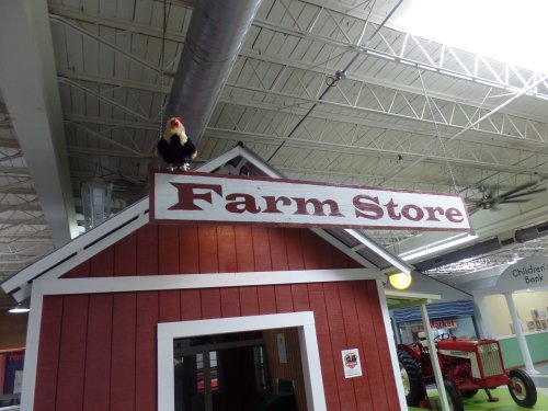 A red barn-style building with a sign reading "Farm Store" and a rooster perched on top.