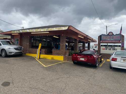 A casual eatery with a brick exterior, outdoor seating, and cars parked outside under a cloudy sky.