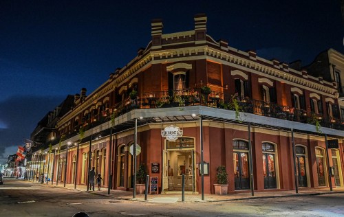 Historic building at night, featuring red brick architecture and balconies, with streetlights illuminating the scene.