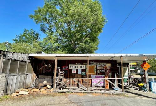 A rustic storefront with a sign for "Sweet Tea," surrounded by trees and blue sky.