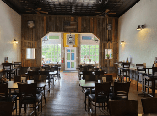 Cozy restaurant interior with wooden walls, tables, and large windows, creating a warm and inviting atmosphere.