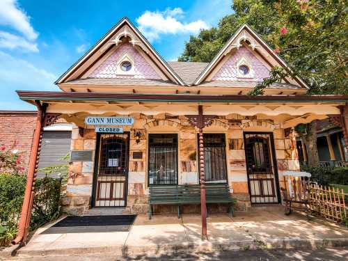 Historic Gany Museum building with a closed sign, featuring decorative architecture and a porch surrounded by greenery.