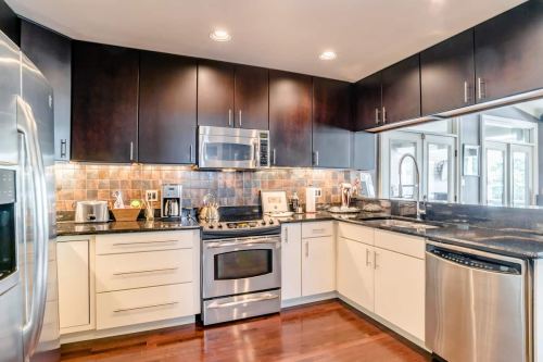 Modern kitchen with dark cabinets, stainless steel appliances, and a stylish backsplash. Bright and spacious design.
