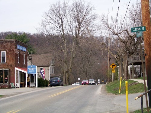A quiet street scene with a small town, featuring shops, bare trees, and a street sign for Clarion St.