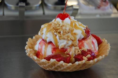 A delicious ice cream sundae in a waffle bowl, topped with whipped cream, cherries, nuts, and caramel drizzle.