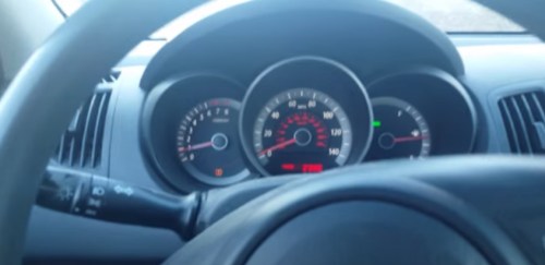 Close-up of a car's dashboard showing speedometer, tachometer, and fuel gauge from the driver's perspective.
