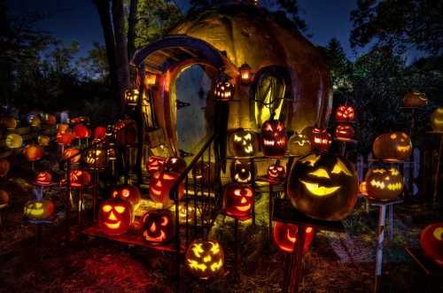 A whimsical pumpkin-shaped house surrounded by glowing jack-o'-lanterns in a nighttime setting.