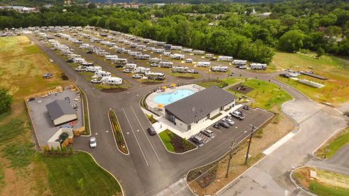Aerial view of a large RV park with numerous parked RVs and a central pool area surrounded by greenery.