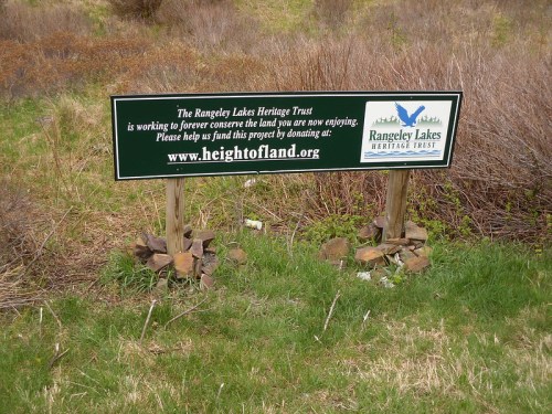 Sign for Rangeley Lakes Heritage Trust, encouraging donations to conserve the land, with a website link for more information.