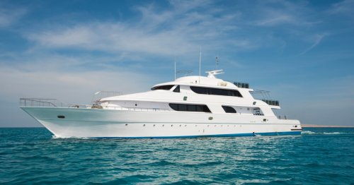 A large white yacht sailing on calm blue waters under a clear sky.