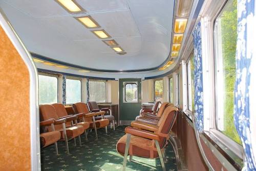 Interior of a vintage train car featuring rows of brown seats and large windows with blue curtains.
