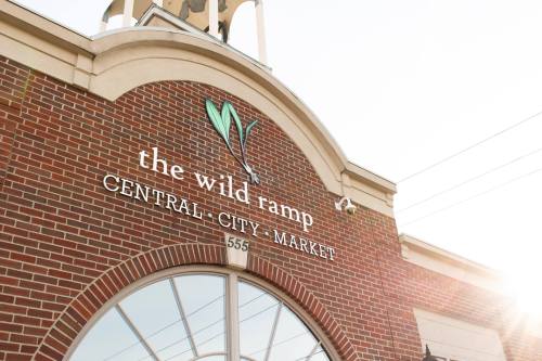 Sign for "The Wild Ramp" at Central City Market, featuring a brick facade and a sunlit background.