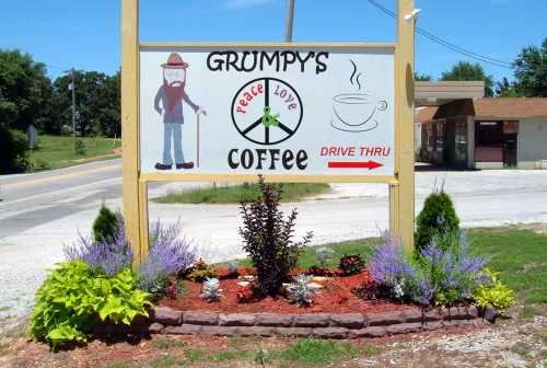 Sign for Grumpy's Coffee featuring a cartoon man, peace symbol, and flowers, with a "Drive Thru" option.