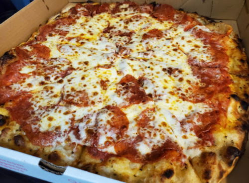 A close-up of a pepperoni pizza with melted cheese, served in a cardboard box.
