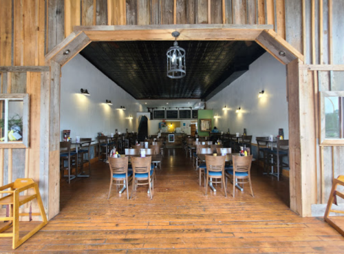 Interior of a rustic restaurant featuring wooden decor, empty tables, and a warm, inviting atmosphere.