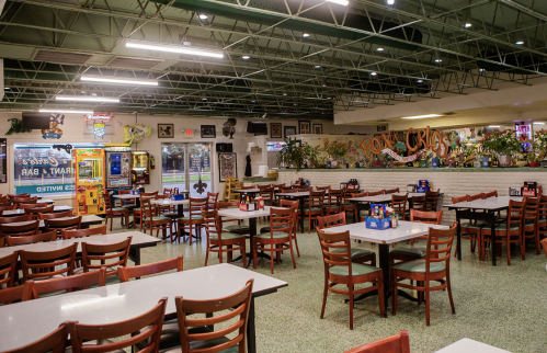 A spacious restaurant interior with empty tables, arcade games, and colorful decor on the walls.