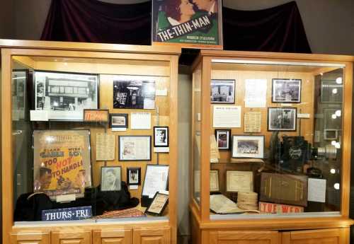 Display cases featuring vintage memorabilia, posters, and photographs related to "The Thin Man" and its history.