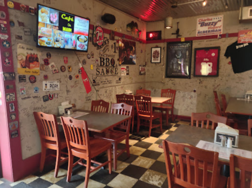 Cozy diner interior with wooden tables, checkered floor, and walls covered in memorabilia and signage.