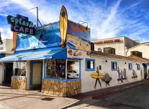 Colorful exterior of The Splash Café with surfboards and beach-themed murals, set against a blue sky.