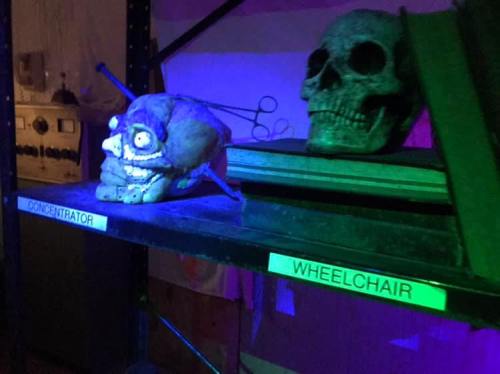 A shelf displays a skull and a creepy, cartoonish skull prop, labeled "CONCENTRATOR" and "WHEELCHAIR."