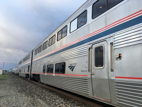 Amtrak sleeping car parked on the tracks under a cloudy sky.